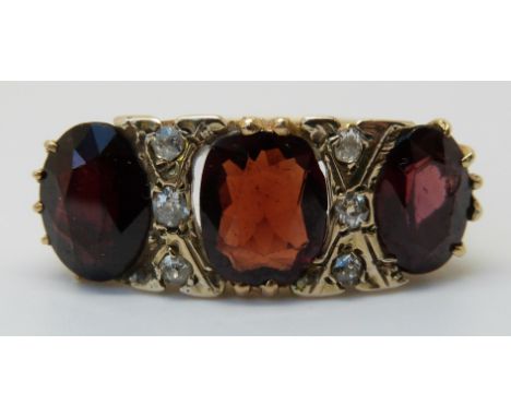 An 18ct gold ring set with large garnets and diamonds (size R )