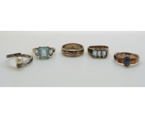 Two silver rings set with blue topaz, a silver ring set with a sapphire, a silver band and a silver ring set with a pearl and