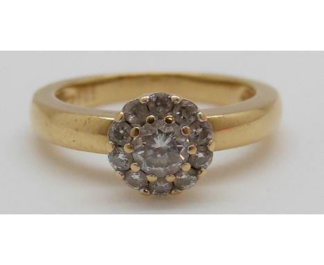 An 18ct gold ring set with a round cut diamond of approximately 0.25ct surrounded by further diamonds, total diamond weight a