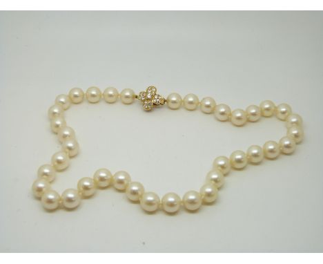 A single strand pearl necklace, the gold clasp set with diamonds in a floral design