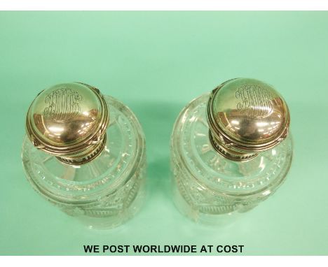 A pair of Fabergé silver topped cut glass scent bottles with ribbon decoration, banding around the tops and line and floral d