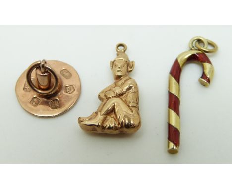 A 9ct gold charm in the form of a candy stick set with red enamel, a 9ct gold charm in the form of a hat and a 9ct gold charm