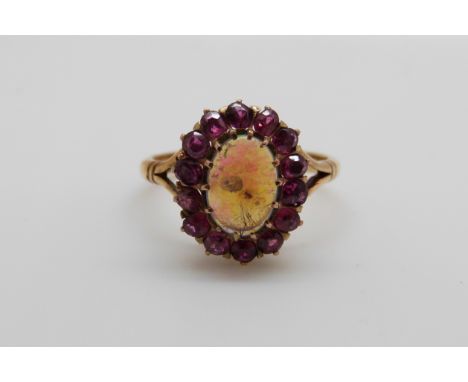 An 18ct gold Victorian ring set with an oval black cabochon surrounded by rubies (size K)