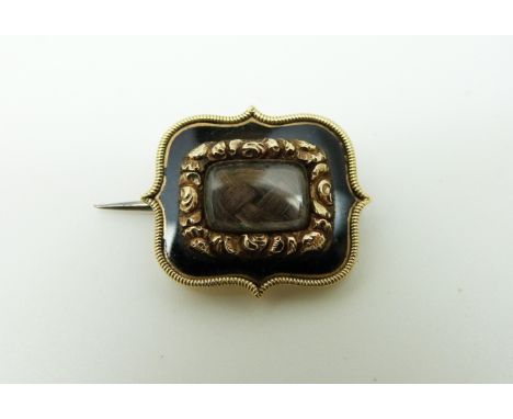 A Georgian mourning brooch set with plaited hair within foliate and black enamel border, verso engraved "Margaret Griffithes 
