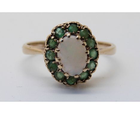 A 9ct gold ring set with an opal surrounded by emeralds (size K)