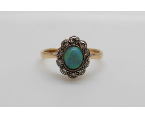 An 18ct gold ring set with a black opal surrounded by old cut diamonds in a platinum setting (size M)