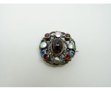 An Austro-Hungarian silver brooch set with a large garnet cabochon to the centre surrounded by blue and green enamel set with