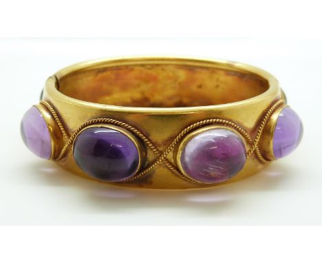 A late Victorian pinchbeck/ yellow metal hinged bangle set with eight large foiled amethyst cabochons within rope twist borde
