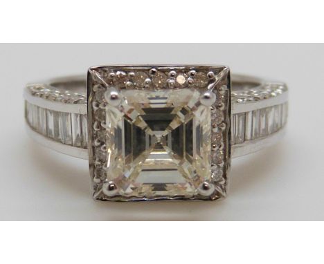 An 18ct white gold ring set with a square cut diamond of approximately 1.5ct surrounded by round cut diamonds and further bag