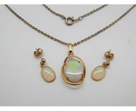 A silver pendant set with an oval opal and a pair of matching earrings 