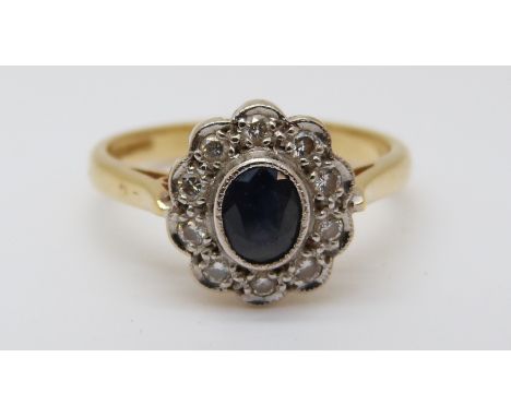 An 18ct gold ring set with a sapphire surrounded by diamonds in a cluster (size K) 