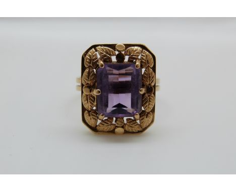 An 18ct gold ring set with an emerald cut amethyst with foliate border, 6.2g, size P 