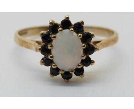 A 9ct white gold ring set with an opal surrounded by sapphires (size Q)