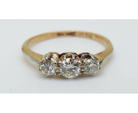 An 18ct gold ring set with three diamonds in a platinum setting, the centre diamond approximately 0.25ct (size K)
