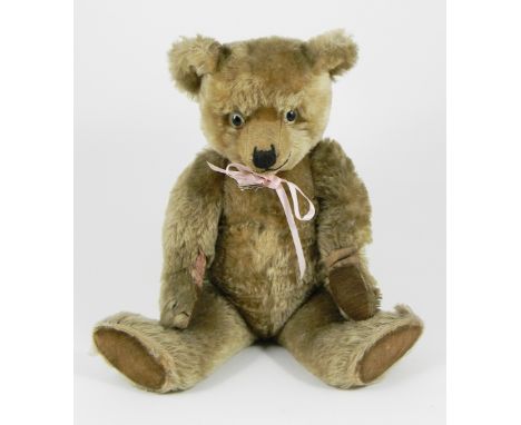 A Chiltern Hugmee Teddy Bear, circa 1930, the light brown mohair bear with large glass eyes, stitched nose, mouth and claws, 