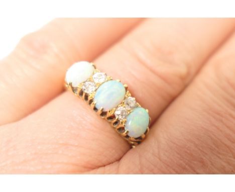 Opal and diamond cluster ring, three cabochon opals dispersed with four small brilliant cut diamonds, all set in yellow gold,