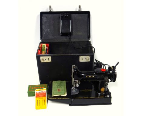 Singer 221K electric sewing machine, with instruction manual, pedal, and accessories including needles, in a carrying case. (