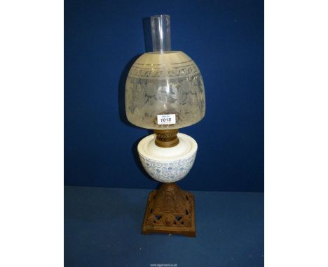 An Oil lamp having cast base, blue and white china reservoir and etched shade, plus chimney.