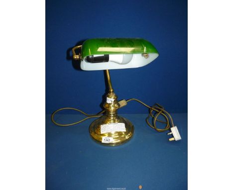 A brass Bankers lamp with green glass shade.