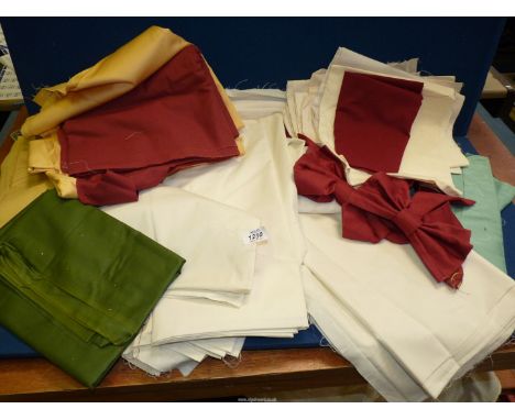 A quantity of lining fabric in various colours including cream, burgundy and gold, curtain bow tie backs etc.