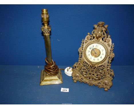 A brass Corinthian column lamp base and an ornate brass table Clock with cherub detail, key present.