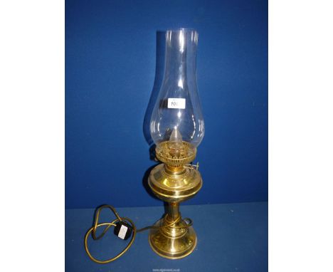 A brass finished Oil lamp converted to electric with clear glass chimney, 24" tall overall.