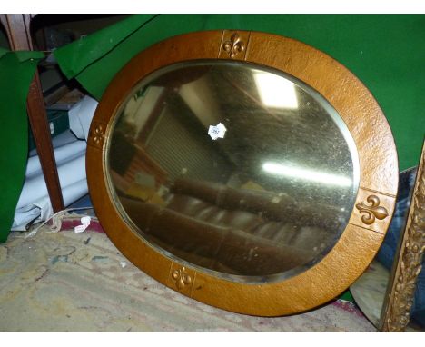 An oval bevel edged Mirror with wooden surround having fleur-de-lys pattern.