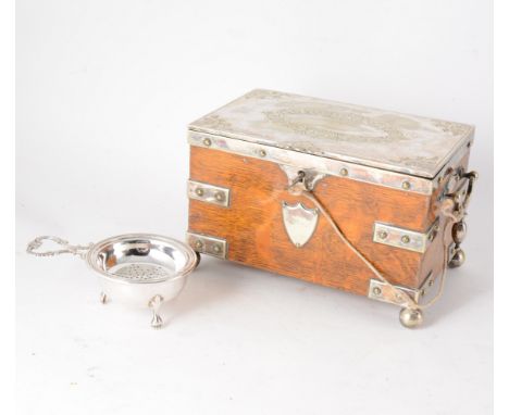 A late Victorian/Edwardian oak tea caddy with silver plated cover, strap work, handles, escutcheon and shield all supported o