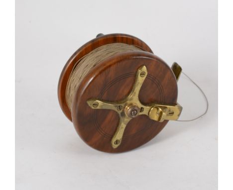 A vintage mahogany and brass star-backed fly fishing reel, 3 3/4", twin black handles, brass foot, stamped 'Made in england',