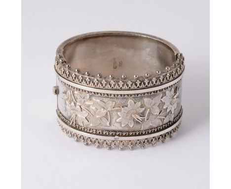 A Victorian silver half hinged bangle, raised detail to front with floral and leaf engraving to centre and a border of fine s