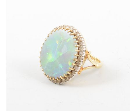 An opal and diamond cluster ring, the oval cabochon cut opal 20mm x 17mm, claw set and surrounded by thirty-two brilliant cut