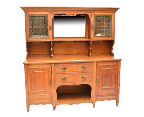 A large late 19th century oak dresser, the moulded cornice above central bevelled mirror and shelf flanked by two leaded stai