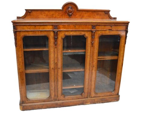 A Victorian pollard oak bookcase with shaped gallery above three drawers above three glazed hinged doors enclosing shelves wi