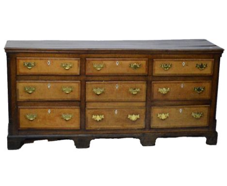 A George III oak and mahogany crossbanded dresser, the rectangular top above seven drawers and central door formed as two dum