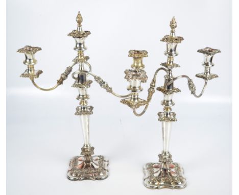 A pair of electroplated three branch candelabra, each convertible to a single candlestick with bell shaped sconces above tape