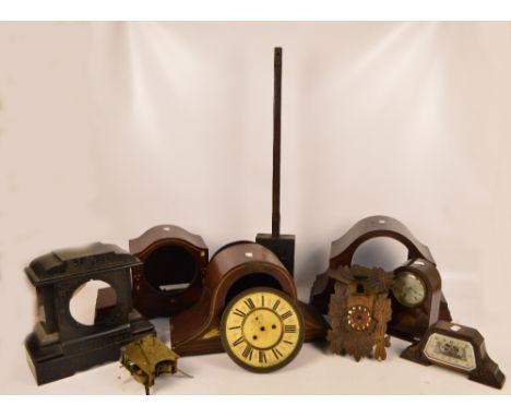 A collection of mantel clock cases, including several wooden examples and a metal example, a cuckoo clock case, several dials