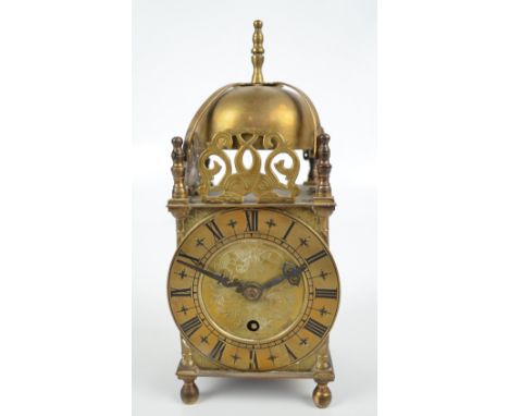 A small mid 20th century brass lantern clock with domed top and pierced dolphin decoration above circular chapter ring set wi