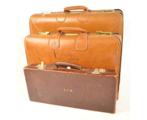 A large canvas trunk with leather mounts and wooden bands, marked C.F., width 73cm, large and small matching suitcases, marke