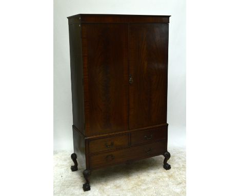 An early 20th century mahogany wardrobe, the left hand door enclosing hanging space, the right hand door set with four short 