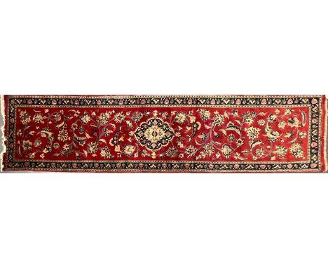 A 20th century Central Persian Islamic Kashan floor carpet runner rug. The rug in a silk red ground with central panel decora