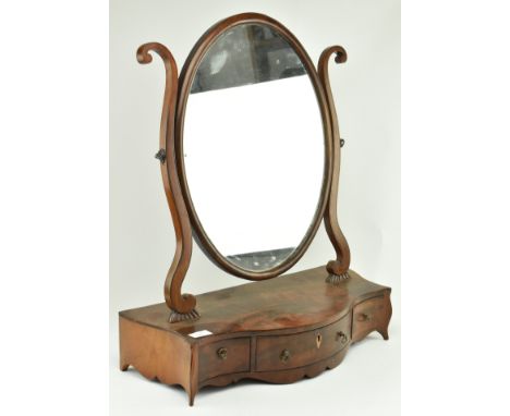 A George III 18th century flame mahogany toilet dressing swing mirror. The mirror having a framed oval mirror plate with scro
