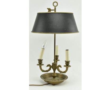 A French brass bouillotte desk lamp light. The lamp having a garland shape carrying ring atop over a dark brass bound shade. 