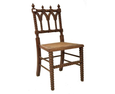 An Arts &amp; Crafts late 19th century Gothic inspired carved oak bobbin turned chair. The chair having turned finials atop o