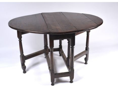 An 18th Century oak oval drop leaf dining table with gate-leg supports, 98cm x 128cm