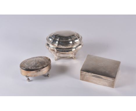 A silver cigarette case with engine turned decoration, a silver trinket box of oval form on ball and claw supports with embos