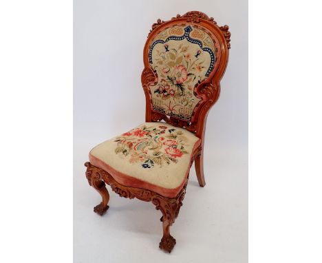 A Victorian carved walnut side chair with ornate scrollwork carving and woolwork tapestry upholstery 