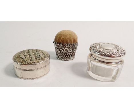 A white metal pin cushion with embossed floral decoration, a silver and glass toiletry pot 3cm tall and a Swedish silver pill