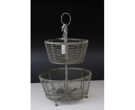 A vintage two tier metal and wire egg stand with ring topped handle. 