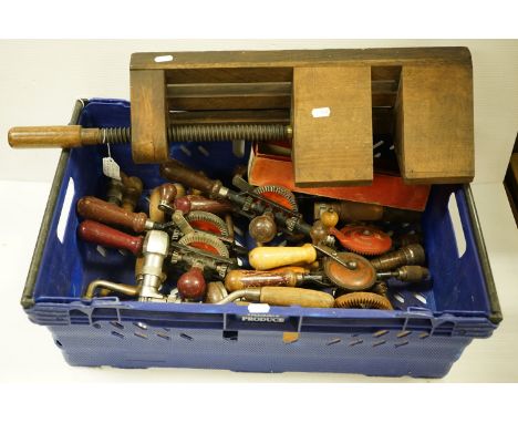 A collection of vintage tools to include a selection of hand drills and a wooden vice. 