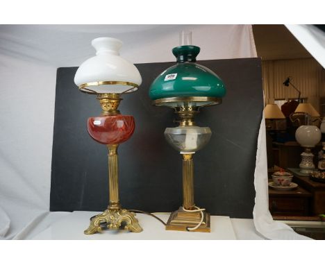 A brass oil lamp converted to electric with cranberry glass well and vaseline shade and one other similar with green glass sh